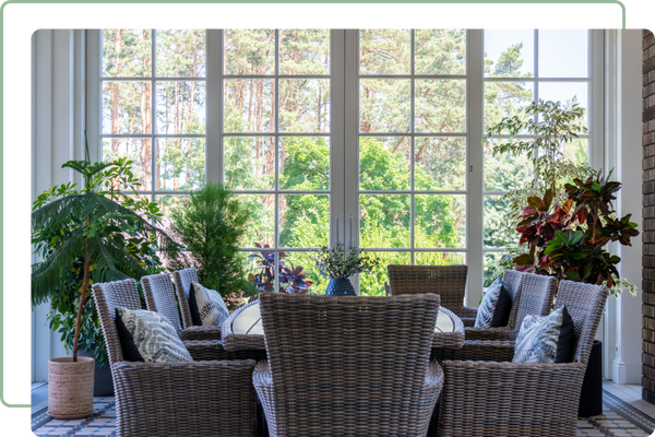 sunroom with windows and french doors behind wicker table and chairs
