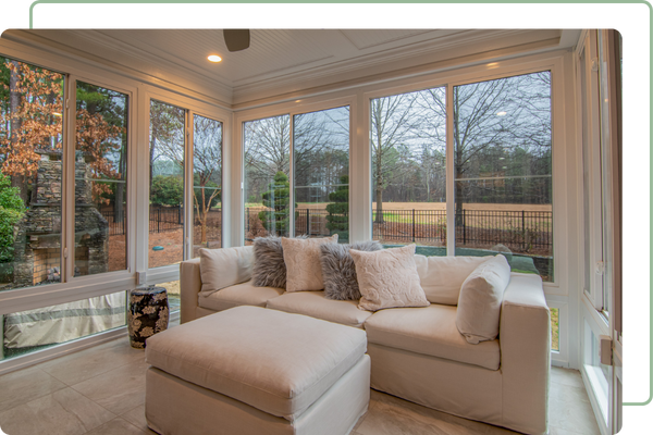sunroom with windows on all sides with a couch and ottoman in the middle of the room