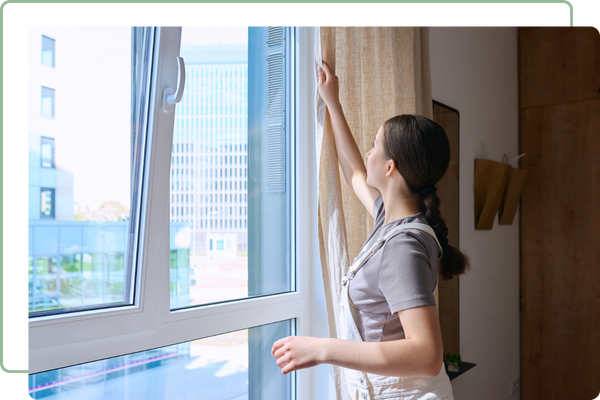 woman opening the curtains of her windows
